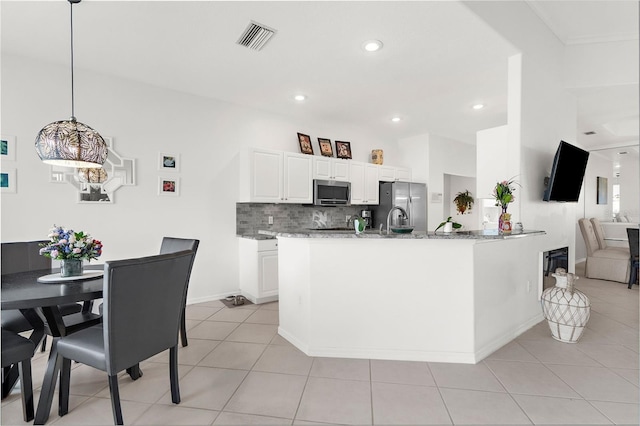 kitchen featuring light stone countertops, tasteful backsplash, stainless steel appliances, decorative light fixtures, and white cabinets