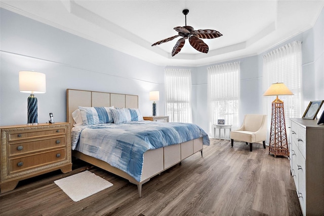 bedroom featuring a raised ceiling, ceiling fan, hardwood / wood-style floors, and ornamental molding