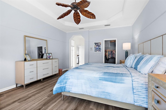 bedroom featuring hardwood / wood-style floors, a tray ceiling, ceiling fan, and crown molding