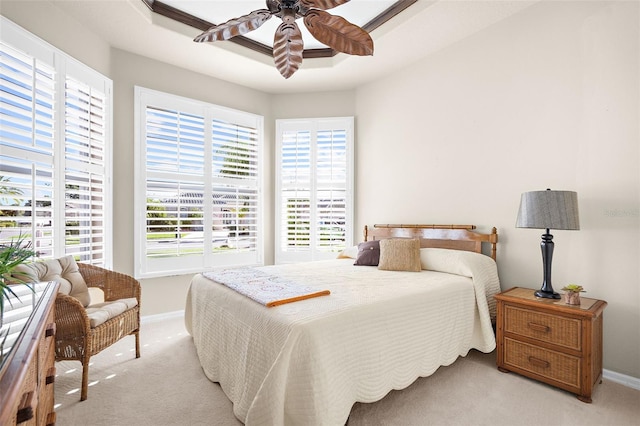 carpeted bedroom featuring ceiling fan and a raised ceiling