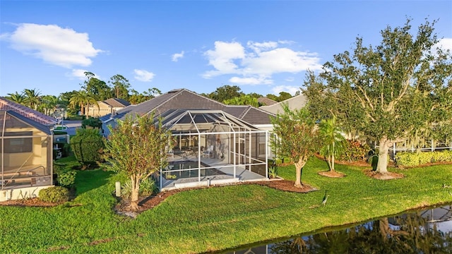 rear view of property featuring a yard, a water view, and a lanai