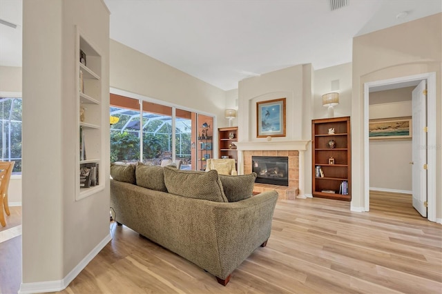 living room with plenty of natural light, a tile fireplace, and light hardwood / wood-style flooring