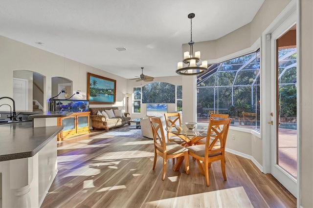 sunroom featuring sink and ceiling fan with notable chandelier