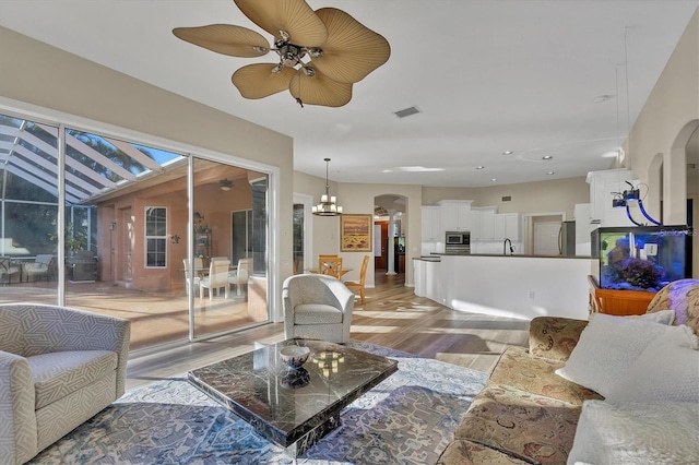 living room with light hardwood / wood-style flooring and ceiling fan with notable chandelier