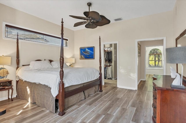 bedroom featuring a closet, a walk in closet, hardwood / wood-style flooring, and ceiling fan