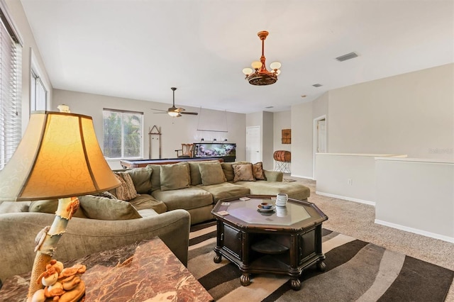 carpeted living room with ceiling fan with notable chandelier