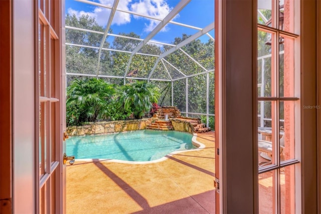 view of pool with glass enclosure and a patio