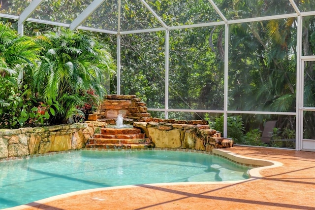 view of swimming pool with glass enclosure, pool water feature, and a patio area