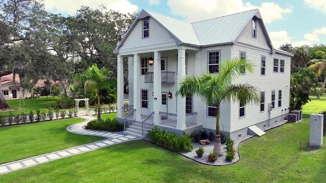 view of front of property featuring a balcony, cooling unit, and a front lawn