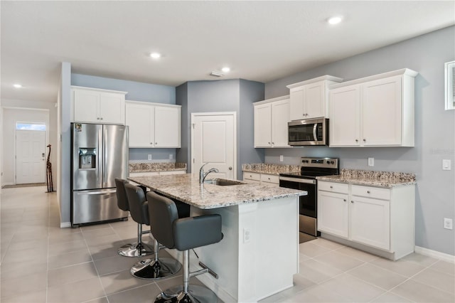 kitchen featuring a center island with sink, white cabinetry, and stainless steel appliances