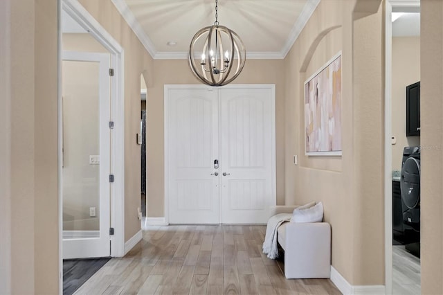 foyer entrance featuring light hardwood / wood-style floors, ornamental molding, and an inviting chandelier