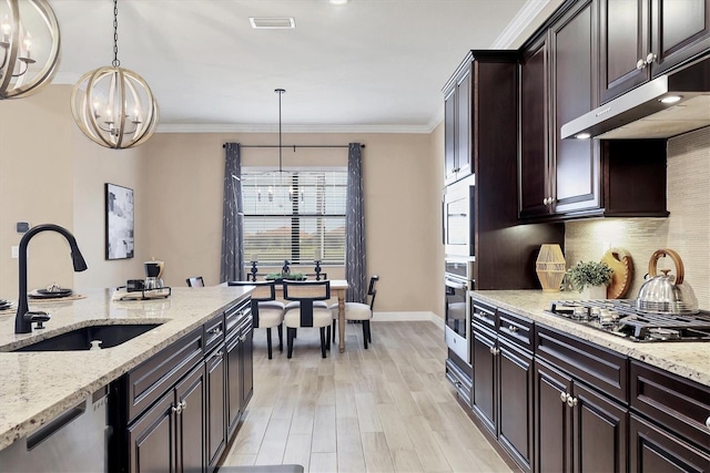 kitchen featuring light stone countertops, sink, hanging light fixtures, and stainless steel appliances