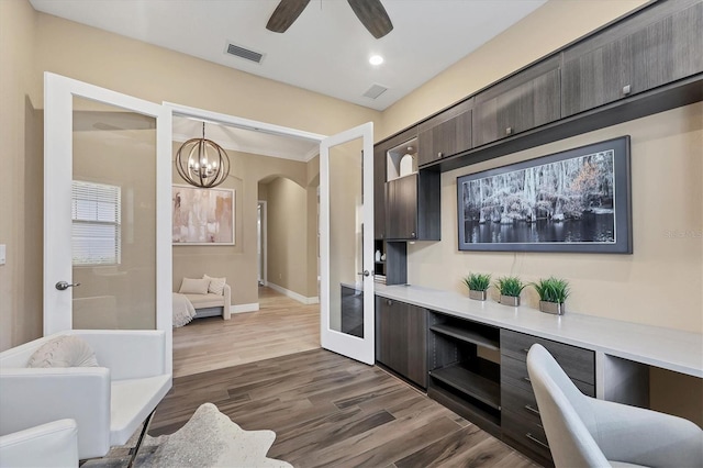 interior space featuring dark brown cabinets, ceiling fan with notable chandelier, pendant lighting, and dark hardwood / wood-style floors