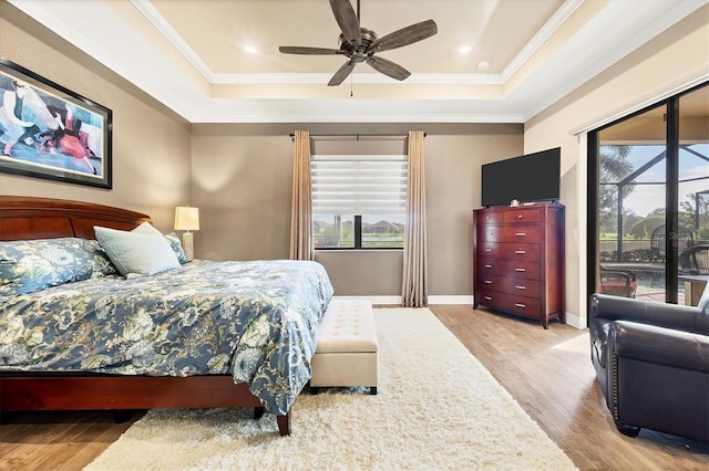 bedroom featuring ceiling fan, light hardwood / wood-style floors, a raised ceiling, and crown molding