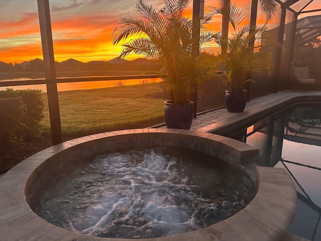 patio terrace at dusk with a water view and a pool with hot tub