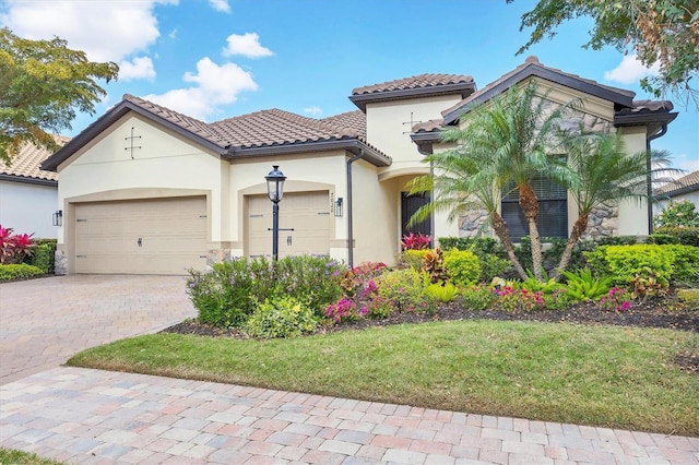 mediterranean / spanish home featuring a garage, decorative driveway, a tiled roof, and stucco siding