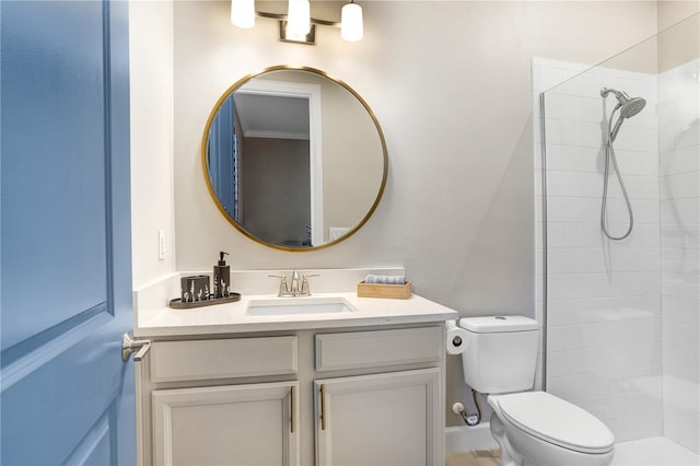 bathroom with toilet, vanity, and a tile shower