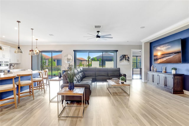 living room with crown molding, light hardwood / wood-style floors, and ceiling fan