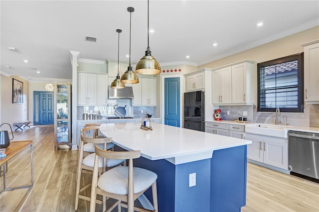 kitchen with tasteful backsplash, appliances with stainless steel finishes, light wood-type flooring, a kitchen island, and pendant lighting