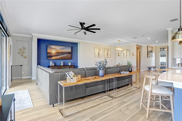 living room with ornamental molding, light hardwood / wood-style flooring, and ceiling fan