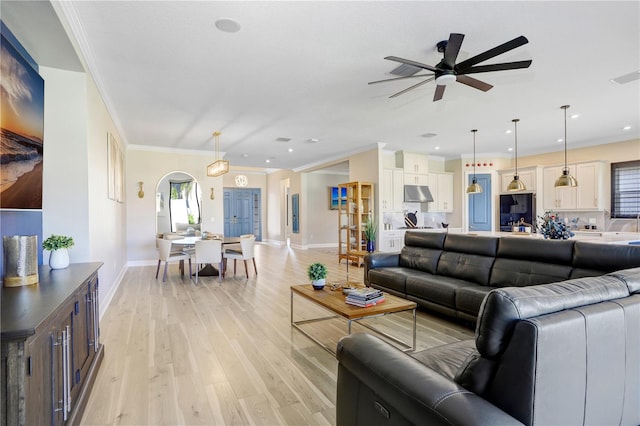 living room featuring light hardwood / wood-style floors, ornamental molding, and ceiling fan