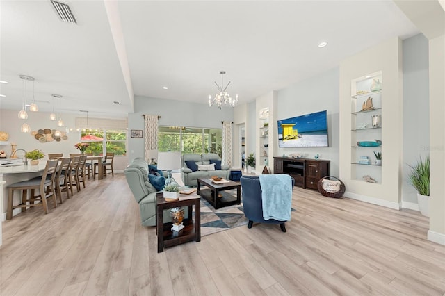 living room with a notable chandelier, light wood-type flooring, and built in features