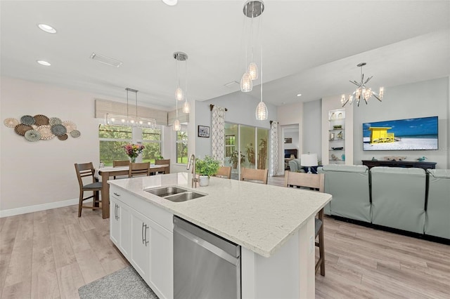 kitchen with hanging light fixtures, white cabinetry, dishwasher, a center island with sink, and sink