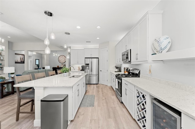 kitchen with white cabinetry, wine cooler, stainless steel appliances, light hardwood / wood-style flooring, and a kitchen island with sink