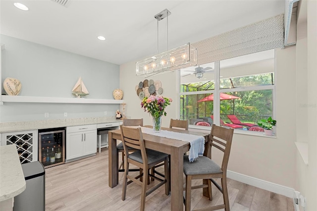 dining area with ceiling fan, bar area, beverage cooler, and light wood-type flooring