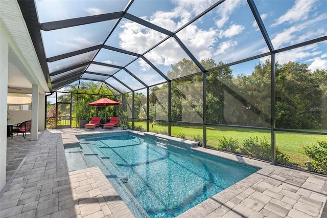 view of pool featuring glass enclosure, a patio, and a lawn