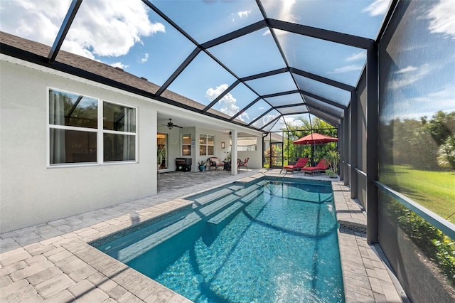 view of pool featuring ceiling fan, glass enclosure, and a patio