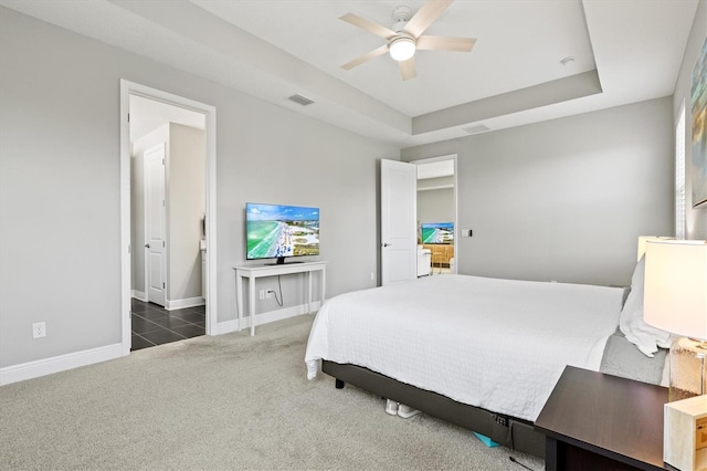 bedroom with a tray ceiling, dark carpet, and ceiling fan