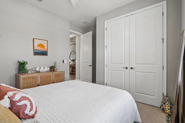 bedroom featuring a textured ceiling, ceiling fan, a closet, and carpet flooring