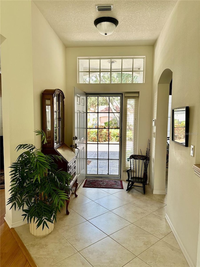 5658 Downham Mdws, Sarasota, FL 34235 - entryway with arched walkways, a textured ceiling, a towering ceiling, visible vents, and light tile patterned flooring