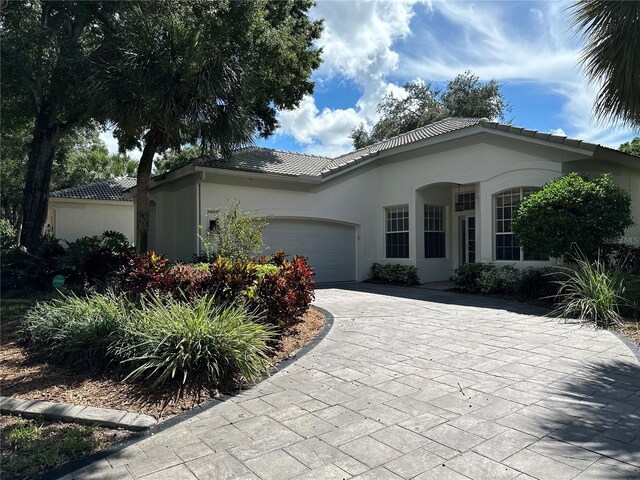 5658 Downham Mdws, Sarasota, FL 34235 - ranch-style house featuring a tiled roof, a garage, stucco siding, and driveway