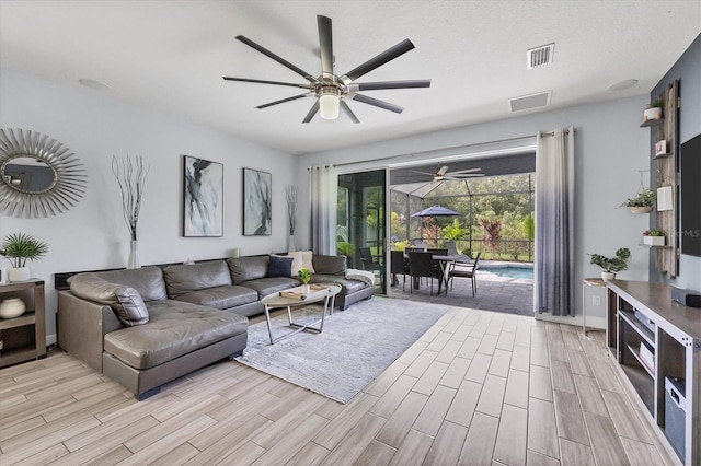 living room with a textured ceiling, light hardwood / wood-style floors, and ceiling fan