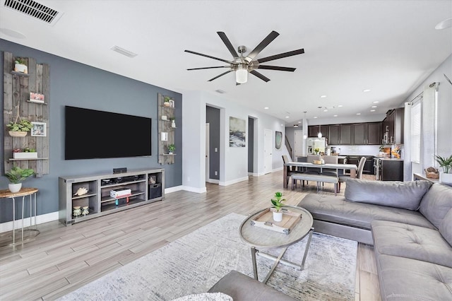 living room with light hardwood / wood-style floors and ceiling fan