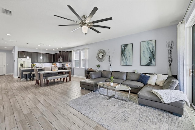 living room with light hardwood / wood-style floors, ceiling fan, and sink