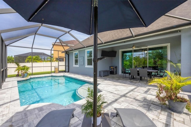 view of pool featuring glass enclosure, ceiling fan, and a patio