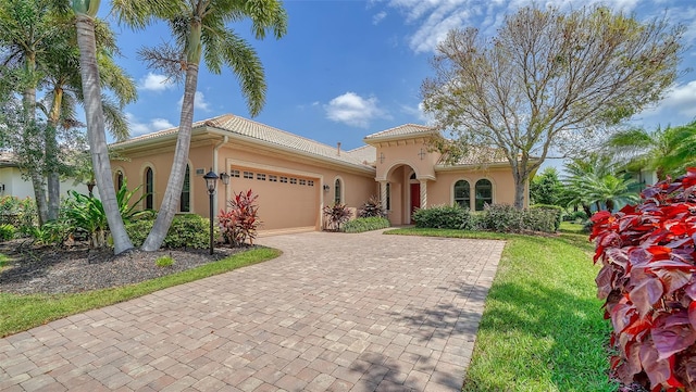 mediterranean / spanish house with a garage and a front lawn