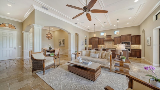 living room with ornamental molding, a towering ceiling, ceiling fan, and ornate columns