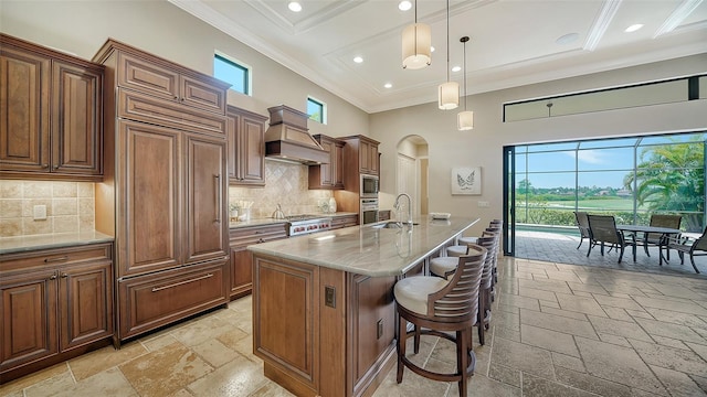 kitchen featuring a kitchen breakfast bar, a center island with sink, sink, and plenty of natural light