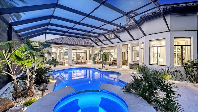 view of pool featuring a patio, glass enclosure, and an in ground hot tub