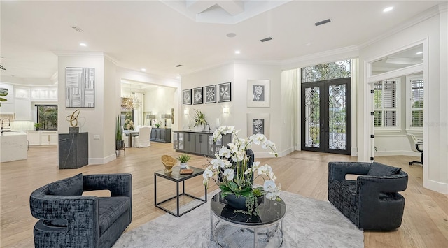 living room with ornamental molding, light hardwood / wood-style floors, french doors, and sink