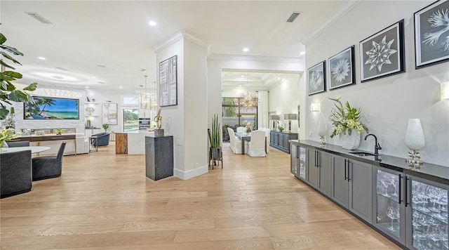 corridor featuring beverage cooler, light wood-type flooring, crown molding, and sink