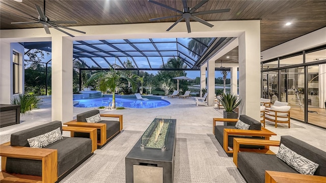 pool at dusk with ceiling fan, a patio, glass enclosure, and an in ground hot tub