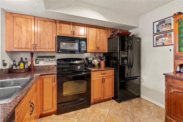 kitchen with light tile patterned floors, sink, a textured ceiling, black appliances, and dark stone countertops