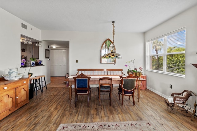 dining space with wood-type flooring and a textured ceiling