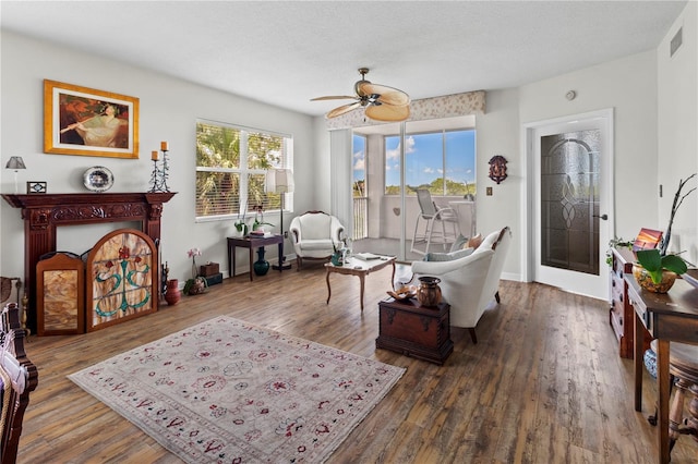 living room with a textured ceiling, dark hardwood / wood-style flooring, and ceiling fan