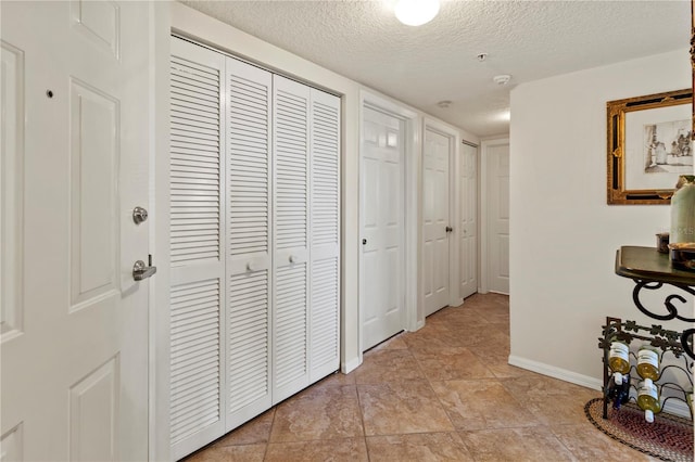 corridor with a textured ceiling and light tile patterned floors